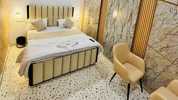 Een moderne slaapkamer met een bed, twee stoelen, een ventilator en een airconditioning.
