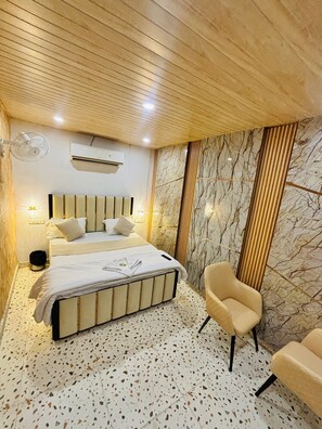 Quarto moderno com uma cama, duas cadeiras, um ventilador e ar condicionado.