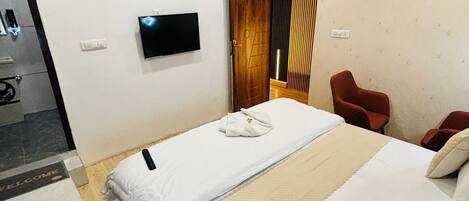 A hotel room with a bed, a TV, an air conditioner, a red chair, and a wooden ceiling.