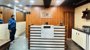 Een hotel receptie met een marmeren balie, houten lambrisering en een bordje dat de receptie aangeeft.