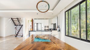 Una cocina amplia con electrodomésticos modernos, una mesa de comedor de madera y un gran ventanal con vistas al verdor.