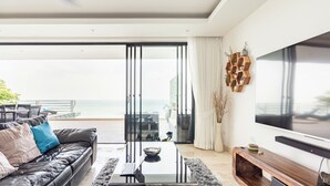 Una sala de estar moderna con un sofá de cuero, una mesa de centro de vidrio y un televisor grande.