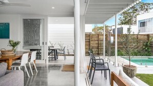 A modern living room with a dining area, a pool, and a view of the backyard.