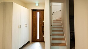 A hallway with a wooden door, a staircase, and a wardrobe.