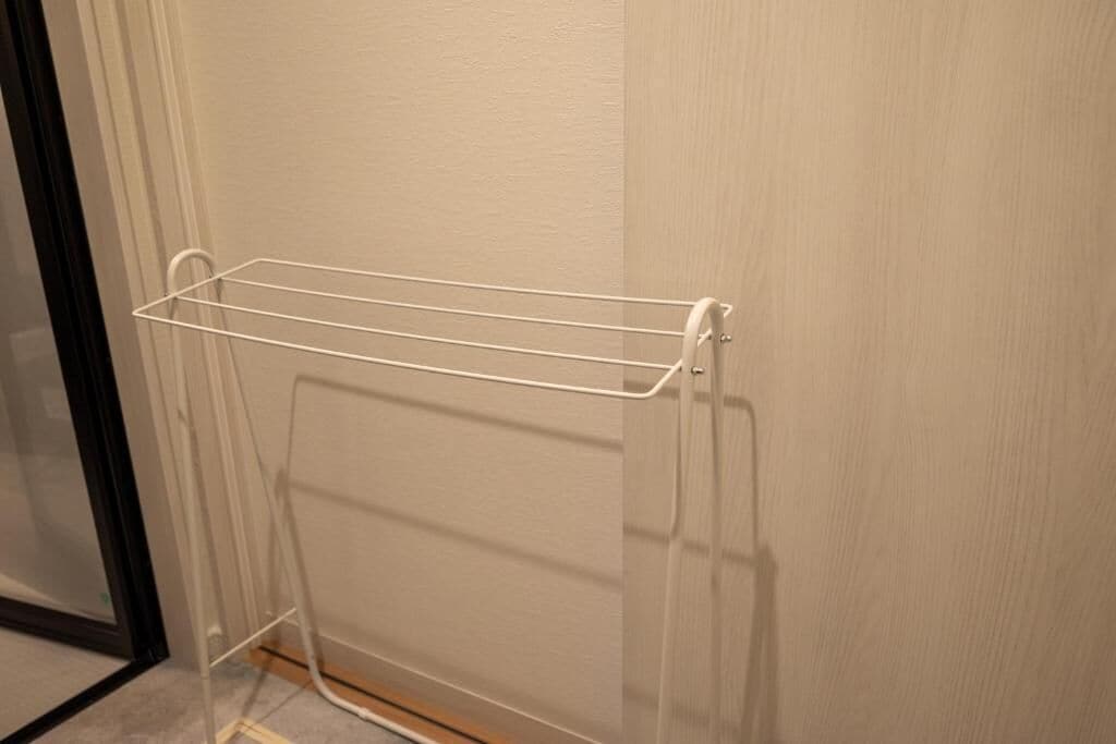 Un tendedero metálico blanco fijado a la pared.