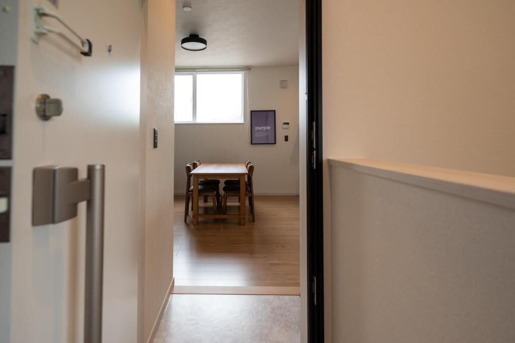 Un couloir avec une table et des chaises en bois, une fenêtre et une porte.