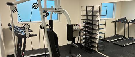 A gym with exercise equipment, a shoe rack, and treadmills.