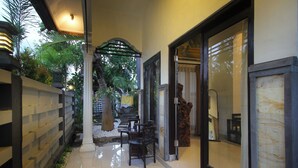 A corridor with a tiled floor, a wooden fence, and a seating area with chairs and a table. - Dhanya Villa Lovina by Parigata (Buleleng)