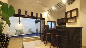 A kitchen with a dining area, a large plant, and a decorative wall with a clock. - Dhanya Villa Lovina by Parigata (Buleleng)