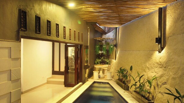 A narrow indoor pool with a wooden ceiling, surrounded by walls with decorative panels and potted plants. - Dhanya Villa Lovina by Parigata (Buleleng)