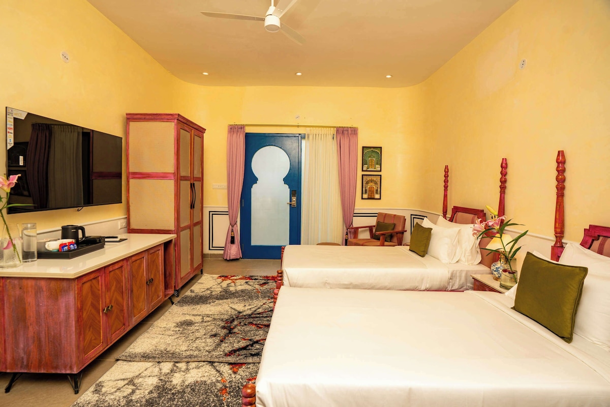 Habitación de hotel con cama, escritorio, televisor, armario y puerta con cortinas.