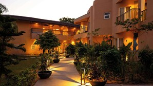A courtyard with potted plants, a pathway, and a building with balconies and lighting. - Sisodia Bagh Luxury Boutique Resort (Amer)