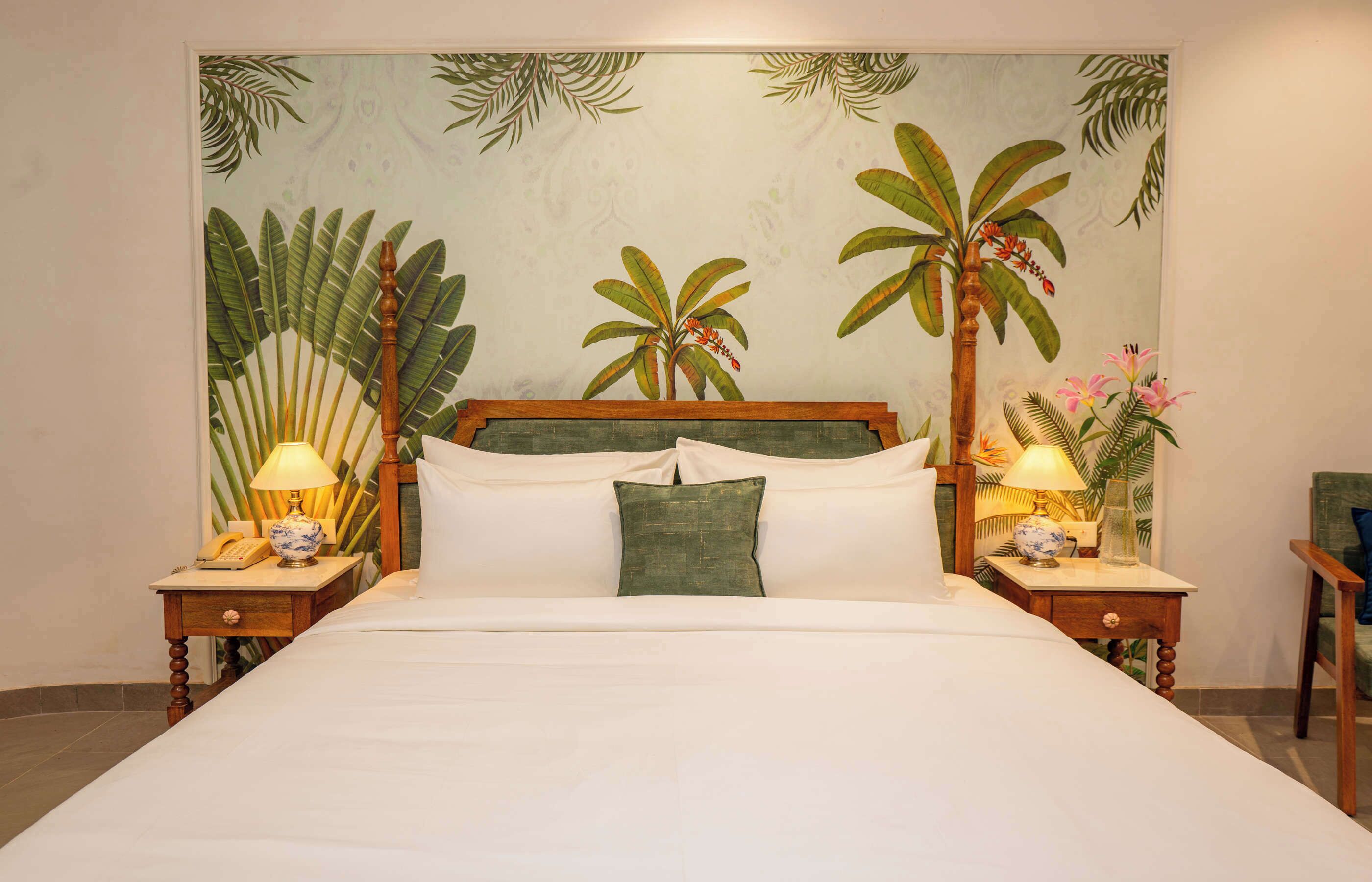 Un letto con testiera in legno, due comodini con lampade e un murale a tema tropicale.