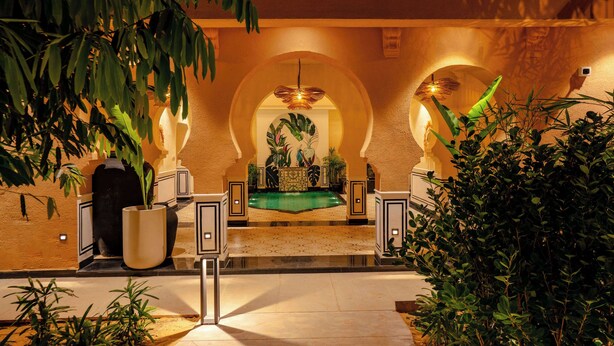 A lobby with a central seating area, a pool, and potted plants. - Sisodia Bagh Luxury Boutique Resort (Amer)