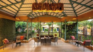 An outdoor patio with a wooden floor, a central round table, and multiple chairs. - Sisodia Bagh Luxury Boutique Resort (Amer)