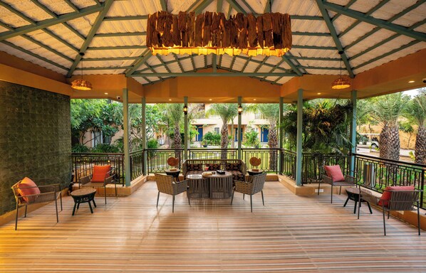 Un patio al aire libre con piso de madera, una mesa redonda central y varias sillas.