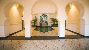 A lobby with a central fountain, arches, and potted plants. - Sisodia Bagh Luxury Boutique Resort (Amer)