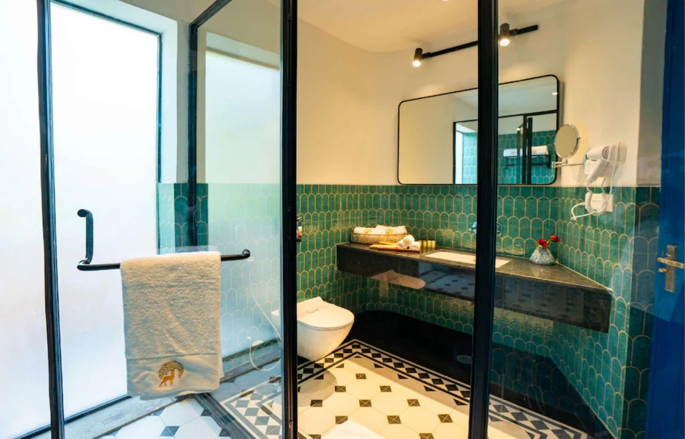 Ein Badezimmer mit Duschkabine, Toilette, Waschbecken mit Spiegel und einem Musterboden.