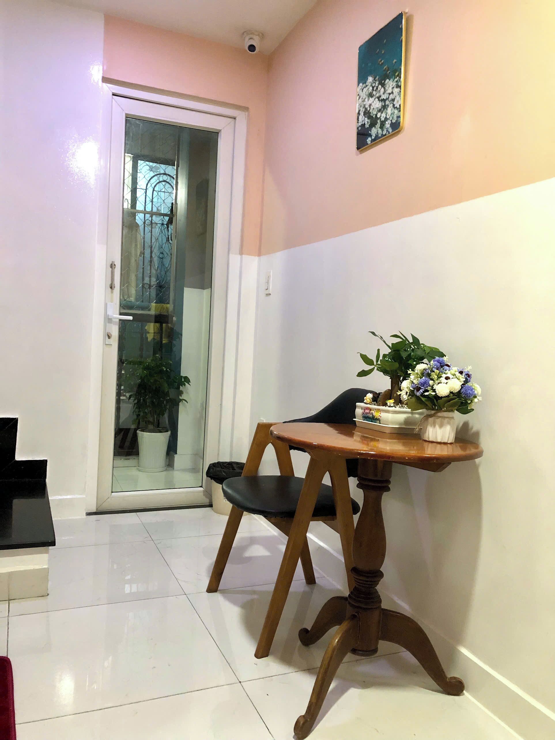 A hallway with a wooden table and chairs, a potted plant, and a door leading to a balcony.