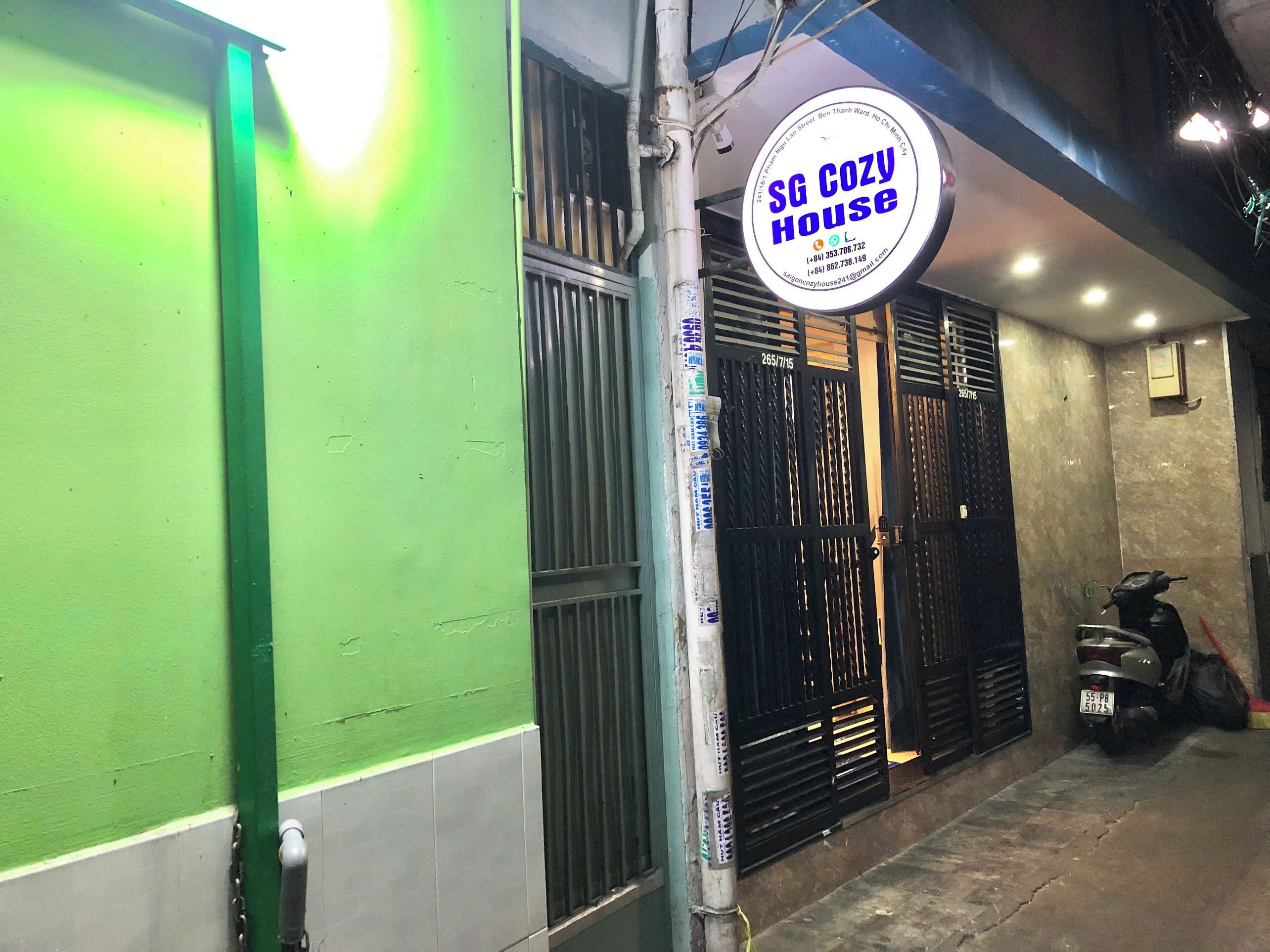 Un edificio con pared exterior verde, un letrero con información de contacto y una verja negra cerrada.