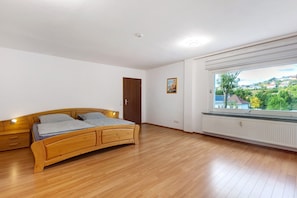 A bedroom with a wooden bed, a window with a view, and a radiator.