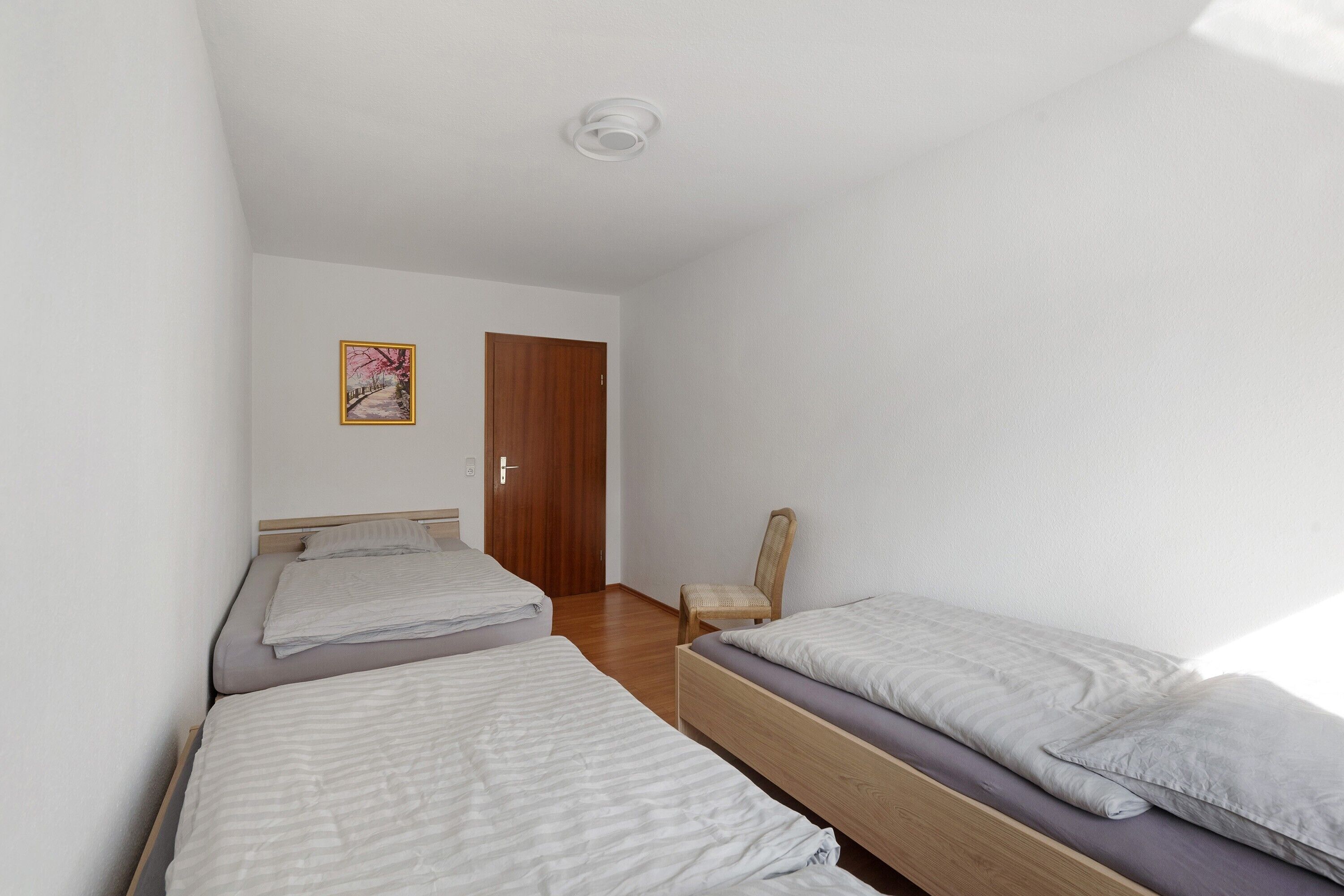 Een kamer met twee bedden, een houten deur en een stoel.