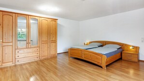 Quarto com cama de madeira, guarda-roupa e mesa de cabeceira.