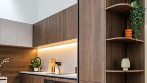 Een moderne keuken met houten kastjes, inbouwapparatuur en een plant op de plank.