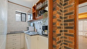 A compact kitchen with a microwave, sink, and cabinets. - Modern 3-Bedroom Stay | Walk to Shops & Dining (Robertson)