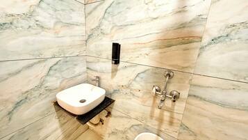 A bathroom with a marble sink, a black soap dispenser, and a modern faucet.