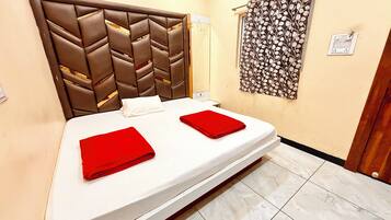 Habitación de hotel con cama, cabecera, una pared con toma de corriente y una puerta.