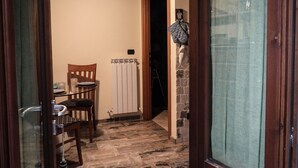 Een smalle gang met een houten stoel, een radiator en een stenen muur.