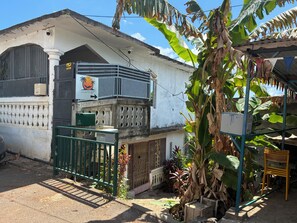 Un bâtiment blanc doté d’un balcon, d’une porte verte et d’une enseigne indiquant la présence d’un restaurant.