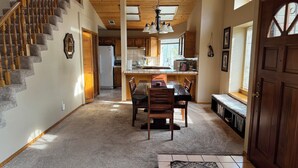 A spacious kitchen with wooden cabinets, a dining area with a table and chairs, and a staircase with wooden balusters. - Family Friendly 3-bedroom house in lovely Three Rivers with AC (Three Rivers)