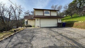 A two-story house with a garage, a satellite dish, and a driveway leading to the garage. - Family Friendly 3-bedroom house in lovely Three Rivers with AC (Three Rivers)