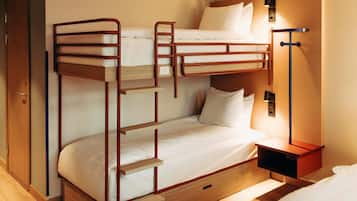 A bunk bed room with a wooden ladder, a bedside table with a lamp, and a wardrobe.