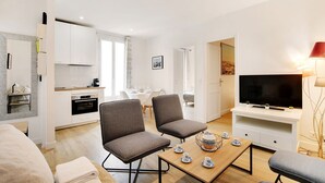 A modern living room with a TV, seating, and a dining area.