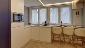 Eine moderne Küche mit integriertem Mikrowellenherd, einem Fenster mit Vorhängen und einer Bar mit Hockern.
