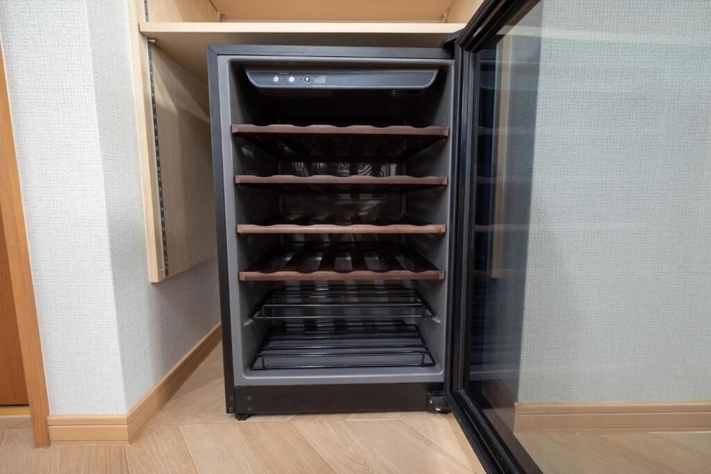 A compact, built-in oven with multiple racks, located in a corner of a room with light-colored walls and wooden flooring.