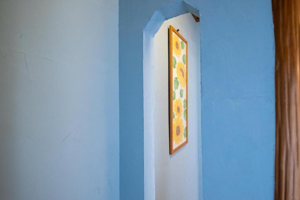 A hallway with a blue wall and a framed picture of sunflowers.
