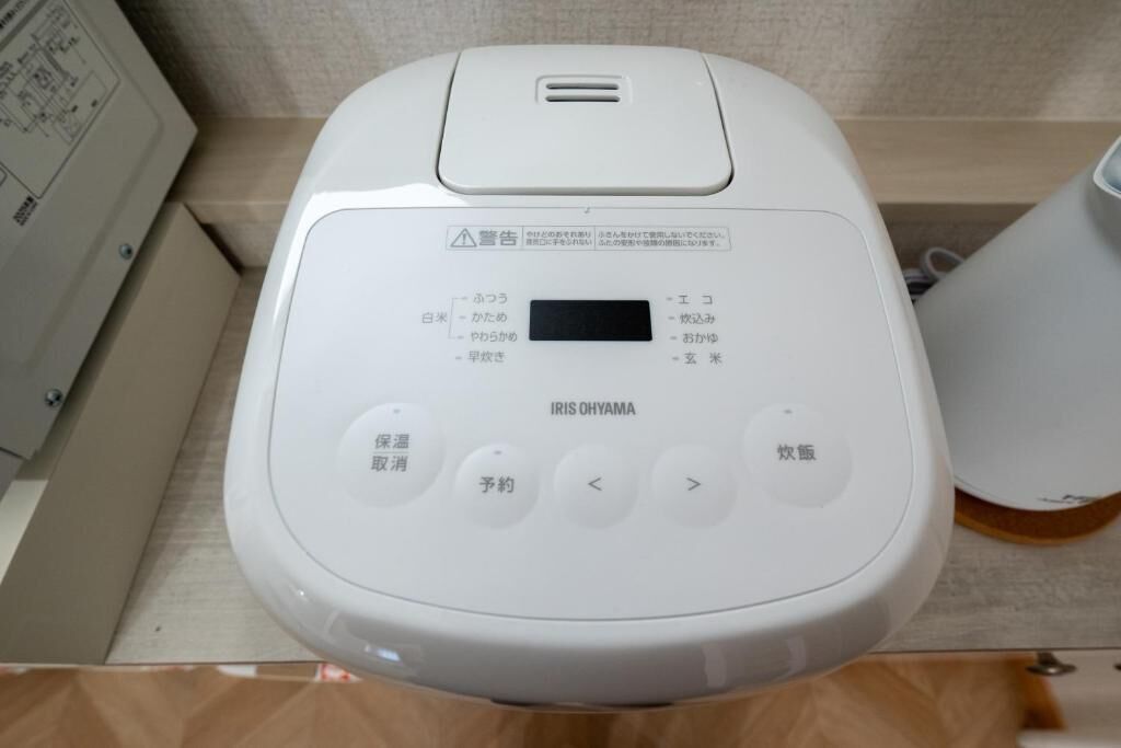 Een wit, draagbaar apparaat met Japanse knoppen en een scherm, waarschijnlijk een draagbare koffiemachine of een vergelijkbaar apparaat.