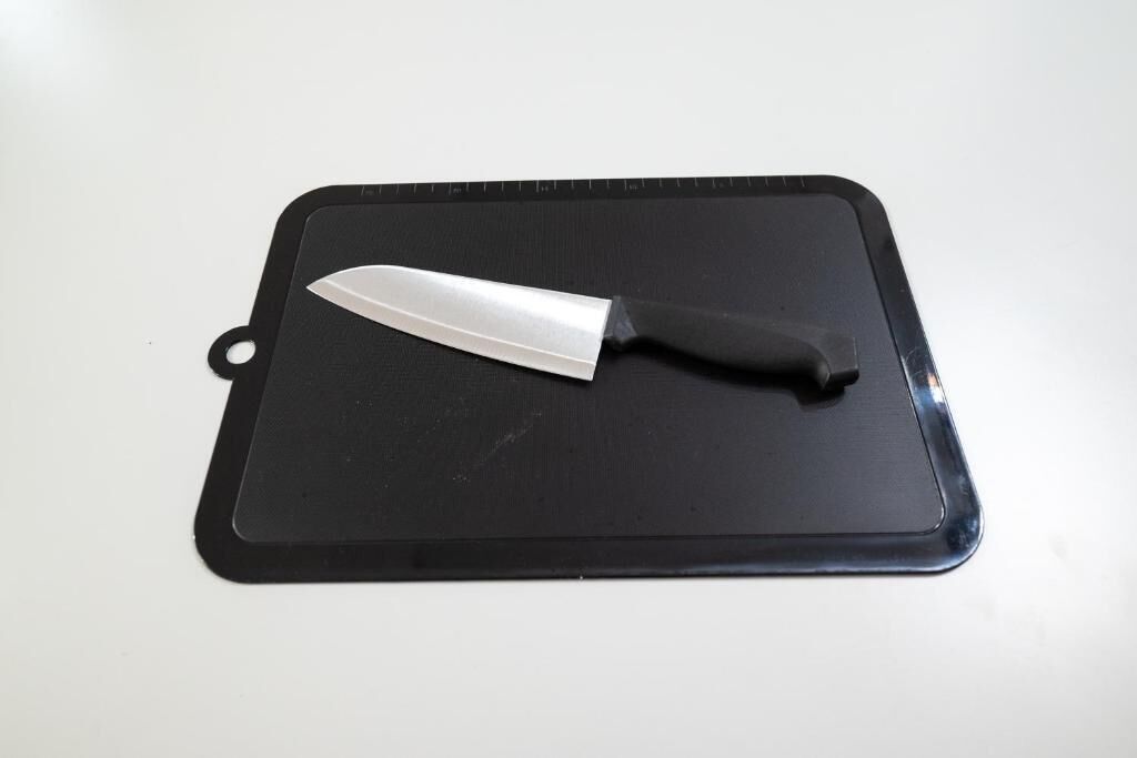 A black cutting board with a knife on it.