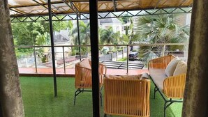 A covered outdoor seating area with wicker furniture and a view of a residential street. - Casalavoro Residence (Abuja)