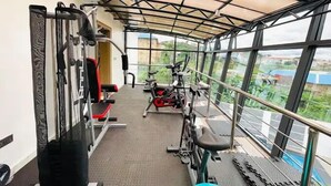 A gym with various exercise equipment, large windows, and a view of the surrounding area. - Casalavoro Residence (Abuja)