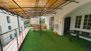 A covered outdoor area with artificial grass, a seating area with chairs, and a railing. - Casalavoro Residence (Abuja)