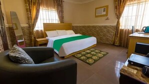 A hotel room with a bed, a chair, a desk, and a mirror. - Casalavoro Residence (Abuja)
