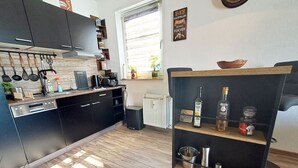 A modern kitchen with dark cabinets, a wooden countertop, and a built-in wine rack.