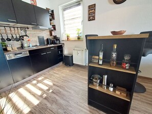 A modern kitchen with dark cabinets, a wooden countertop, and a built-in wine rack.