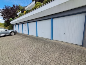 A building with multiple garage doors, a paved driveway, and a parked car.