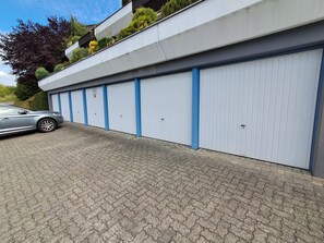 Ein Gebäude mit mehreren Garagentoren, einer gepflasterten Auffahrt und einem parkenden Auto.